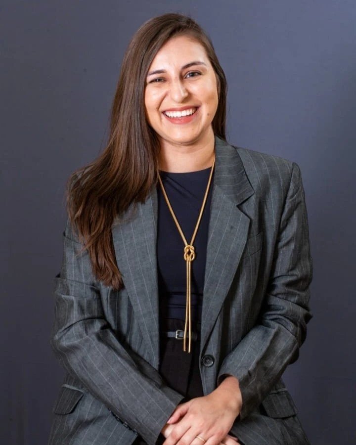 Retrato profissional de Mirelle Christina Pinheiro, sorrindo, de blazer cinza